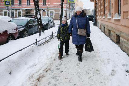 Санкт-Петербург. Женщина с ребенком идет по неубранной от снега улице.