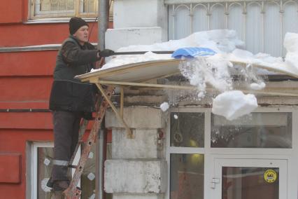 Иркутск. Мужчина сбрасывает снег с крыши.