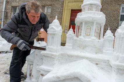 Санкт-Петербург.  Петербуржец Владимир Кузьмин во время изготовления снежной скульптуры Исаакиевского собора во вдоре своего дома.