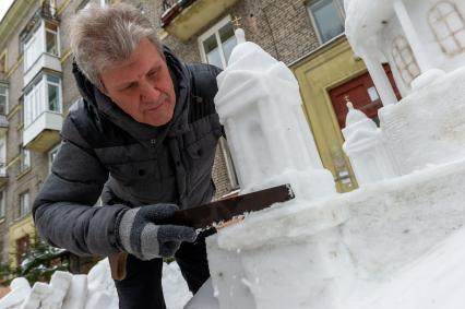 Санкт-Петербург.  Петербуржец Владимир Кузьмин во время изготовления снежной скульптуры Исаакиевского собора во вдоре своего дома.