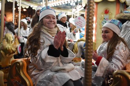 Москва. Участницы парада Снегурочек, проходящего в рамках фестиваля `Путешествие в рождество`, катаются на карусели.