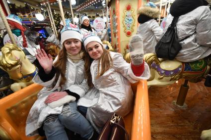 Москва.  Участницы парада Снегурочек, проходящего в рамках фестиваля `Путешествие в рождество`, катаются на карусели.