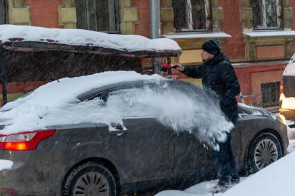 Санкт-Петербург. Мужчина счищает снег с автомобиля.