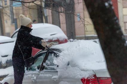 Санкт-Петербург. Женщина счищает снег с автомобиля.