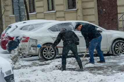 Санкт-Петербург. Мужчины расчищают двор от снега.