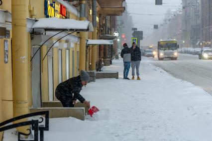 Санкт-Петербург. Женщина чистит тротуар от снега.