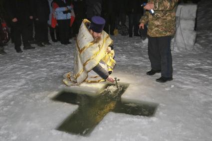 Барнаул. Священник православным крестом освящает воду перед крещенскими купаниями в праздник Крещения Господня.
