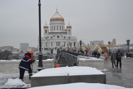 Москва. Сотрудник коммунальных служб убирает снег у храма Христа Спасителя.