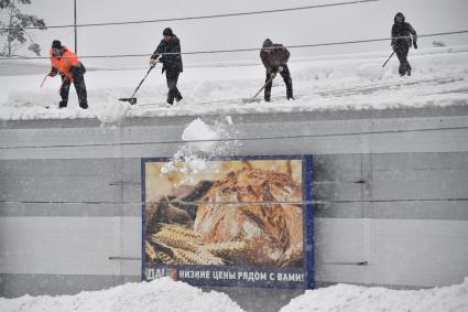 Москва.  Сотрудники коммунальных служб счищает снег с крыши.