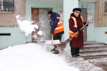 Нижний Новгород. Работники коммунальных служб убирают снег у подъезда жилого дома.