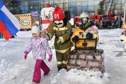 Москва. Ростовые куклы в форме пожарных во время проведения флешмоба пожарных и спасателей МЧС `Растопис снег вместе!` на ВДНХ.