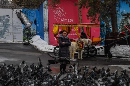 Казахстан, Алма-Ата. Женщина кормит голубей у Вознесенского собора Астанайской и Алматинской епархии Русской православной церкви на территории парка имени 28 гвардейцев-панфиловцев.