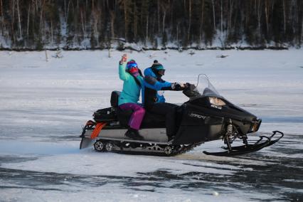 Красноярский край. Молодые люди едут на снегоходе  по льду Красноярского водохранилища.