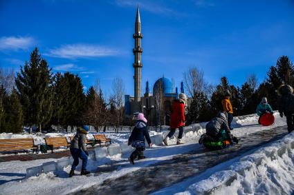 Казахстан, Усть-Каменогорск. Дети катаются с ледяной горки в парке у Мечети  Мухамади.