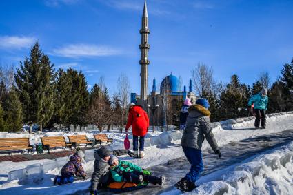 Казахстан, Усть-Каменогорск. Дети катаются с ледяной горки в парке у Мечети  Мухамади.