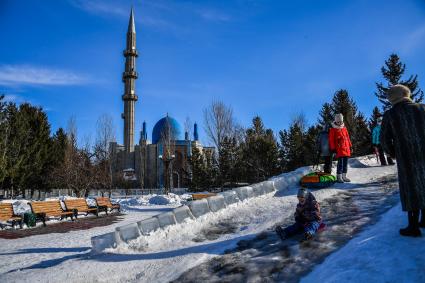 Казахстан, Усть-Каменогорск. Дети катаются с ледяной горки в парке у Мечети  Мухамади.