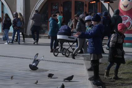 Москва. Девочка кормит голубей на Манежной площади.