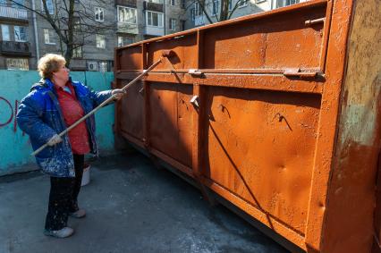 Санкт-Петербург. Сотрудник ЖКХ красит мусорный контейнер.