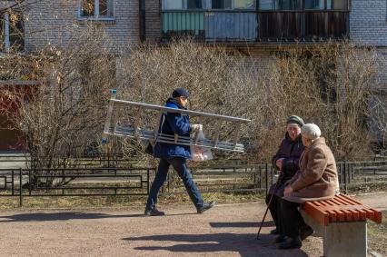 Санкт-Петербург. Сотрудник ЖКХ с лестницей во дворе дома.