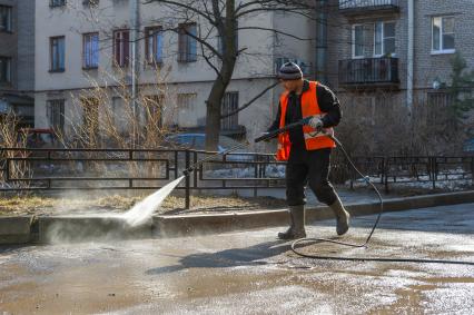 Санкт-Петербург. Сотрудник  ЖКХ убирает внутридомовую территорию.