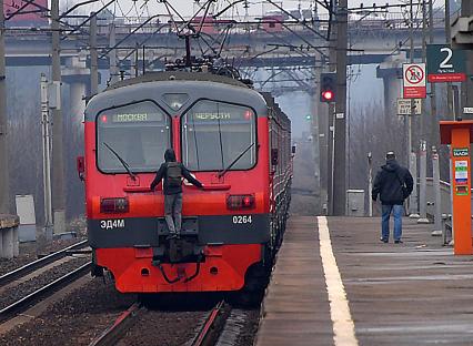 Москва. Молодой человек `зацепер `прикрепился к последнему вагону электрички на одной из пригородных платформ.
`