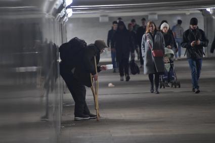 Москва.  Мужчина с костылями просит милостыню в подземном переходе.