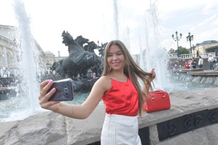 Москва. Девушка фотографируется у фонтанов на Манежной площади.
