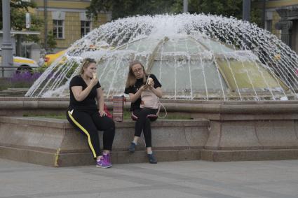 Москва. Женщины едят мороженое у фонтана на Манежной площади.