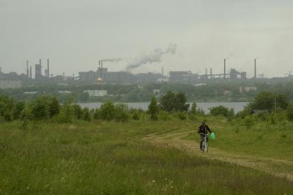 Свердловская область. Нижний Тагил. Мужчина на велосипеде едет по пустырю, где планируется строительство моста