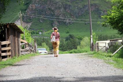 Горный Алтай, село Анос. Женщина идет по сельской дороге.