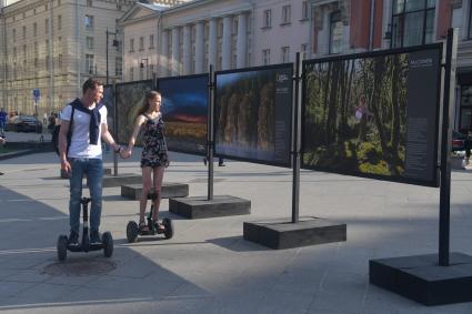 Москва.  Молодые люди на сегвеях осматривают уличную фотовыставку на Кузнецком мосту.