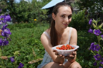 Самара. Девушка собирает ягоды на дачном участке.