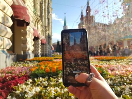 Москва. Девушка фотографирует на фестивале цветов у ГУМа.