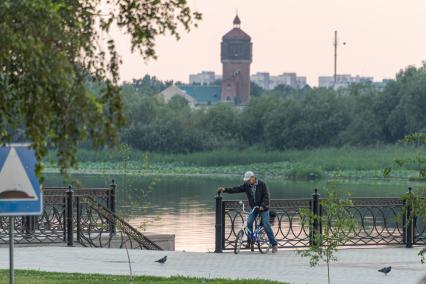 Астрахань. Мужчина с велосипедом на городской набережной.