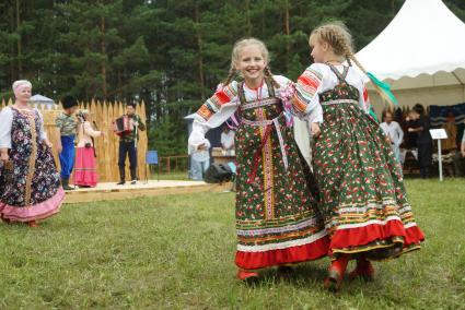 Свердловская область. Празднование Сабантуя на территории конно-спортивного клуба \'Белая лошадь\'. Девочки в русской традиционной одежде танцуют во время ярмарки