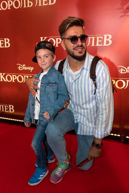 Москва. Футболист Евгений Савин с сыном на премьере фильма Disney `Король Лев` в кинотеатре `Каро 11 Октябрь` на Новом Арбате.