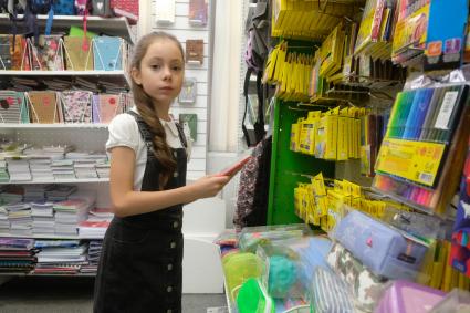 Санкт-Петербург.  Девочка в отделе школьных принадлежностей в магазине канцтоваров перед началом учебного года.