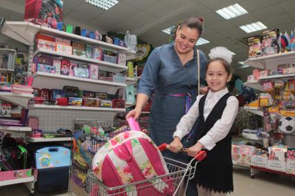 Иркутск. Девочка  и женщина выбирают школьный рюкзак в торговом зале магазина.