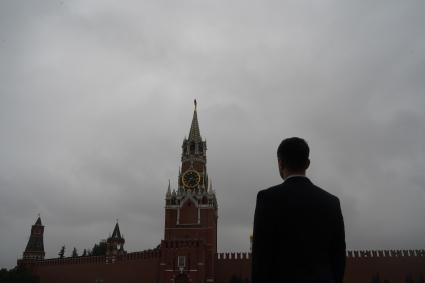 Москва. Мужчина в костюме на Красной площади смотрит на Спасскую башню Кремля.