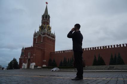 Москва. Мужчина в костюме на Красной площади смотрит на Спасскую башню Кремля.