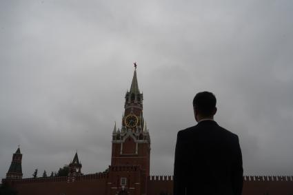 Москва. Мужчина в костюме на Красной площади смотрит на Спасскую башню Кремля.