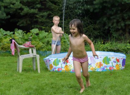 Московская область.  Мальчик поливает девочку водой из шланга.