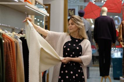 Санкт-Петербург. Женщина пенсионного возраста выбирает одежду в магазине.