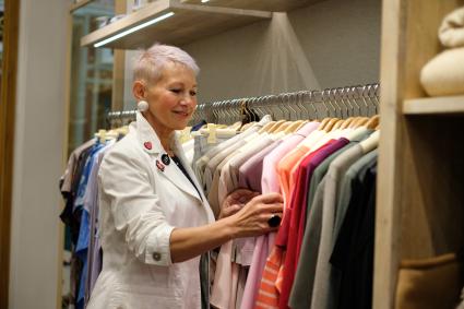 Санкт-Петербург. Женщина пенсионного возраста выбирает одежду в магазине.