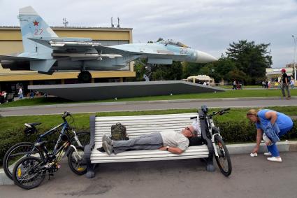 Москва.  Мужчина отдыхает на скамейке у павильона `Космос`.