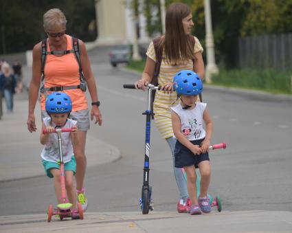 Москва.  Женщины с детьми на самокатах.