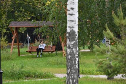 Москва. Женщина на качелях в Детском Черкизовском парке.