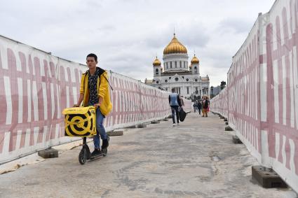 Москва. Сотрудник сервиса по доставке еды `Яндекс Еда` на Патриаршем мосту.