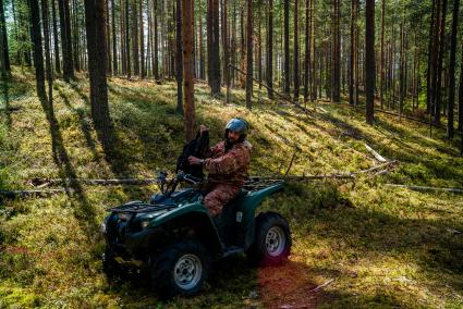 Республика Карелия, Медвежьегорский район. Корреспондент `Комсомольской правды` Дмитрий Стешин на квадроцикле в лесу.