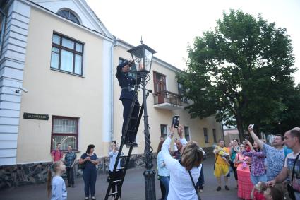 Беларусь, Брест. Фонарщик зажигает фонарь на улице города.